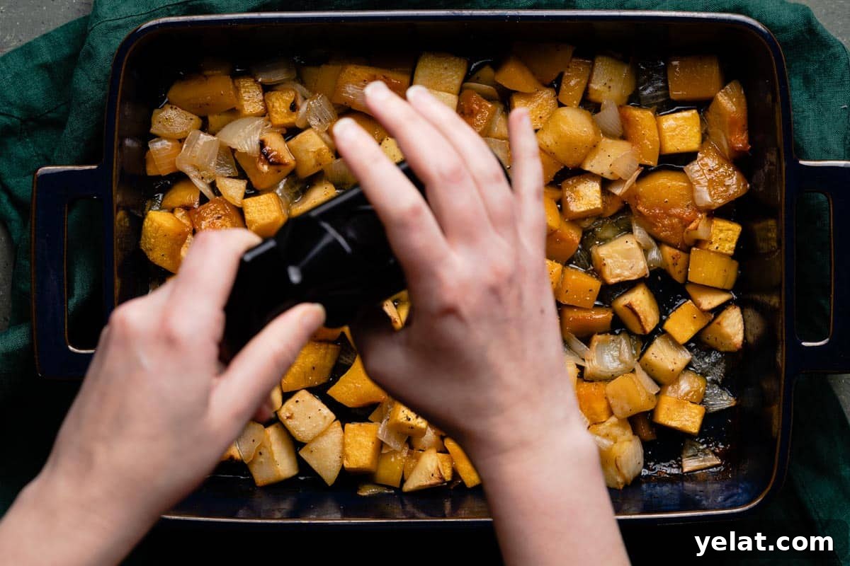 Maple-Glazed Roasted Squash and Apples for Fall Side Dish 12 fresh pepper being ground overtop cooked pan of butternut squash and apples