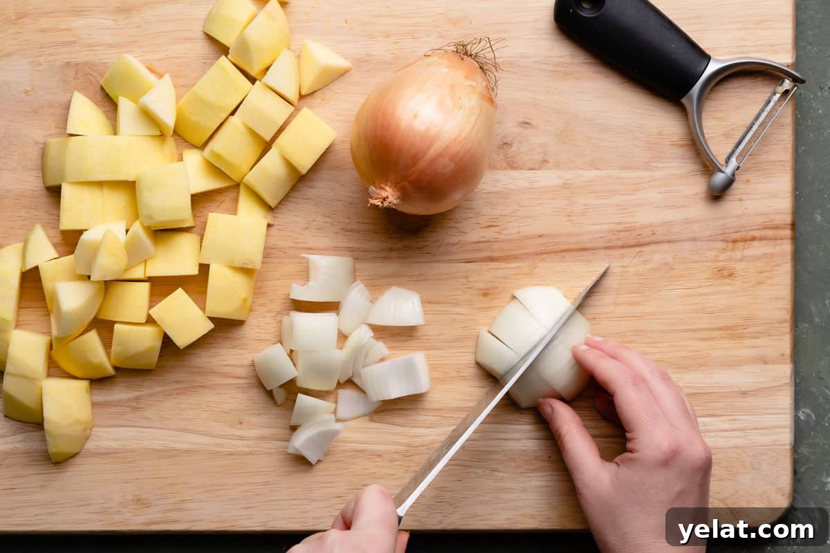Maple-Glazed Roasted Squash and Apples for Fall Side Dish 4 onion being chopped into chunks with chunks of apple on the side