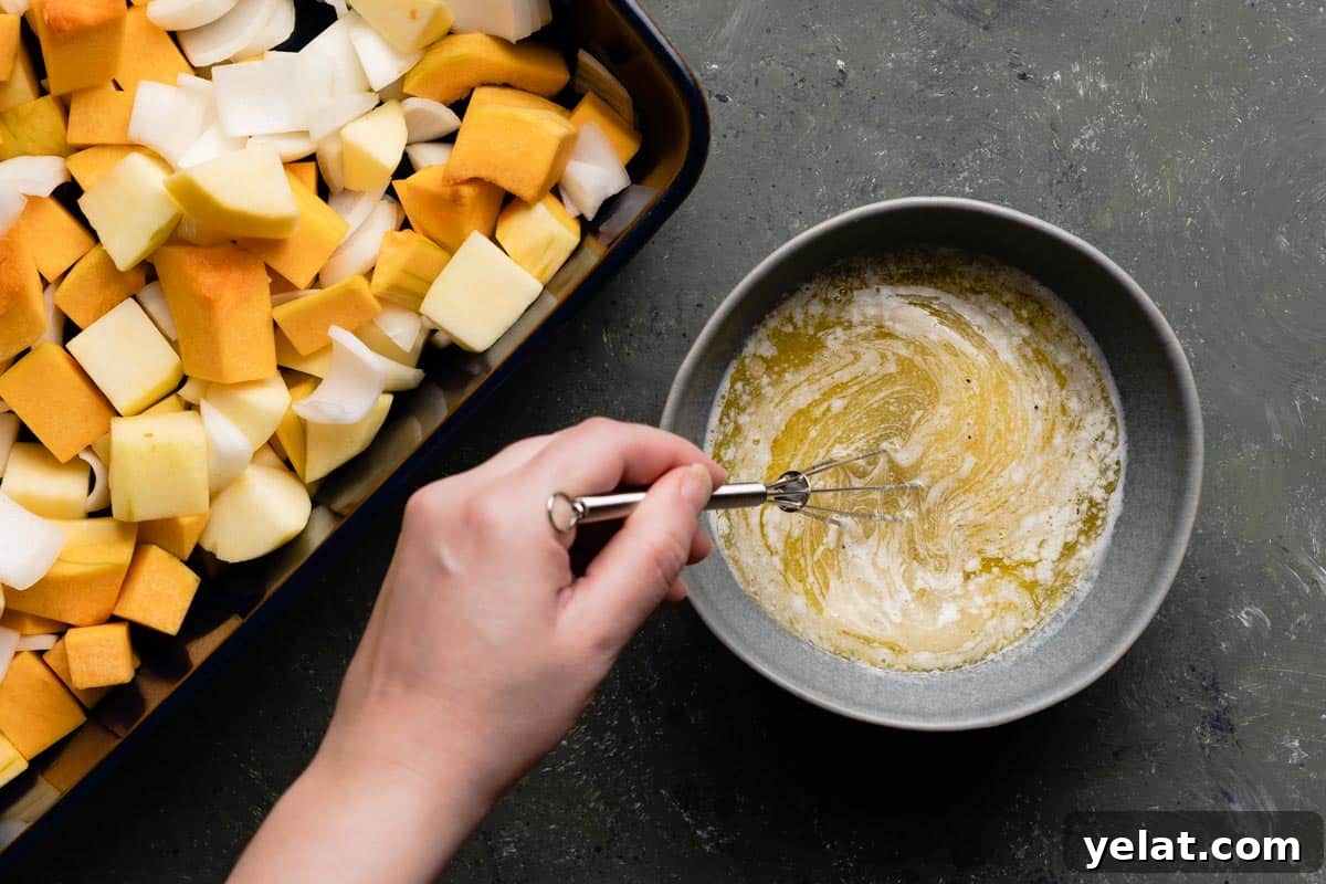 Maple-Glazed Roasted Squash and Apples for Fall Side Dish 8 hand holding small whisk whisking butter mixture in small bowl