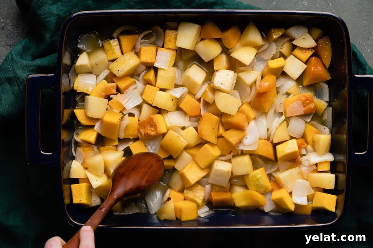Maple-Glazed Roasted Squash and Apples for Fall Side Dish 10 pan of half cooked butternut squash and apples with wooden spoon stirring them
