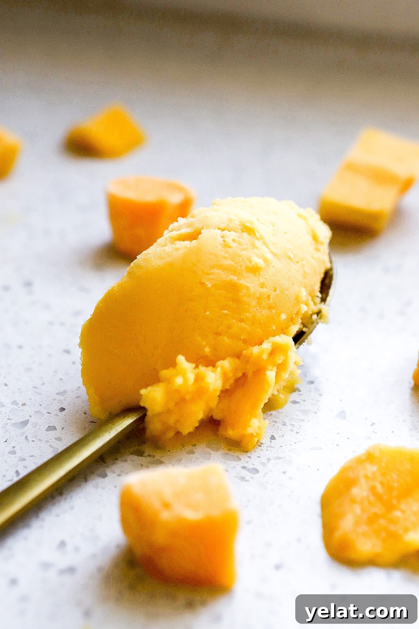 Ninja Creami Mango Sorbet: 3-Ingredient Dairy-Free Recipe 3 Gold spoon full of Ninja Creami mango sorbet with mango chunks