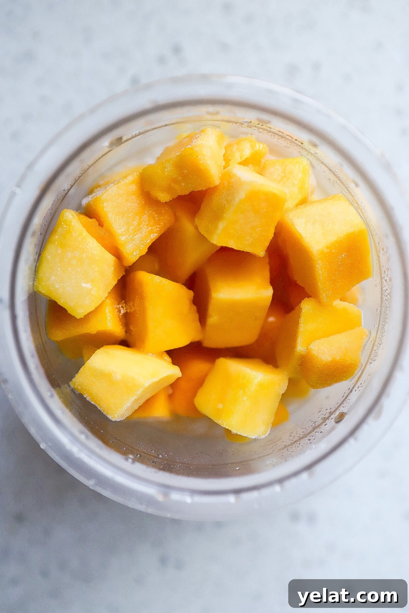 Ninja Creami Mango Sorbet: 3-Ingredient Dairy-Free Recipe 4 Top down view of frozen mango chunks in Ninja Creami pint container