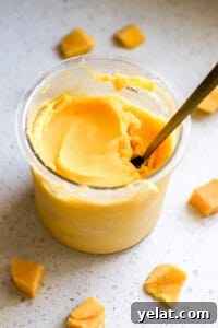 Ninja Creami Mango Sorbet: 3-Ingredient Dairy-Free Recipe 7 Side angle of creamy pineapple sorbet in ninja creami container with gold spoon.