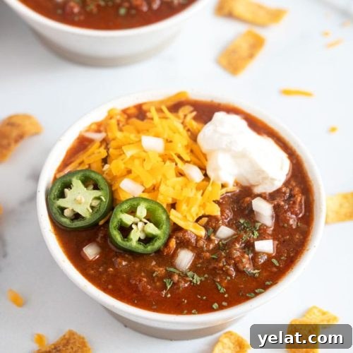 A bowl of chili with assorted toppings.