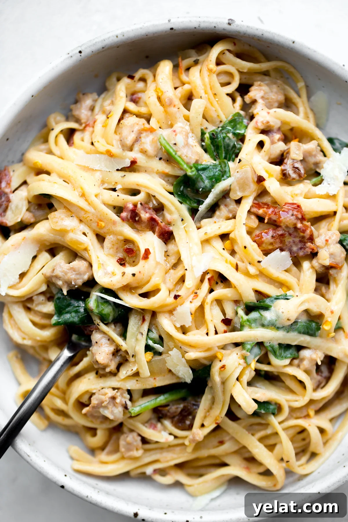 overhead shot of a bowl of instant pot sausage and sun-dried tomato linguine pasta on a white background