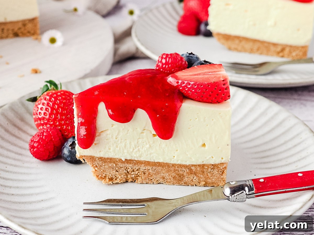 Philadelphia No-Bake Cheesecake Recipe — Creamy, Refrigerator Cheesecake 4 Slice of cheesecake on a plate with fresh berries and drizzle of strawberry sauce, and rest of cake and another slice of cheesecake in the background.