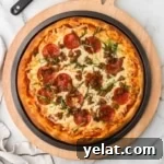 Pizza topped with pepperonis and cheese on a black pan.