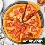 Homemade pizza in a round pan with bowls of seasonings.