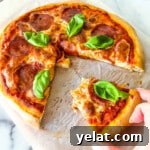 Woman's hand removing slice of homemade pepperoni pizza.