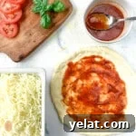 Sauce, cheese, and tomato slices around a crust with sauce.