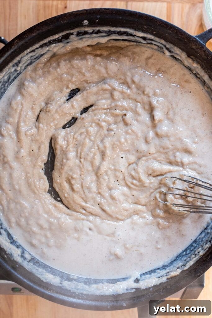 Skillet Buffalo Chicken Macaroni and Cheese Recipe 11 A lumpy roux forming with milk in a cast iron skillet.