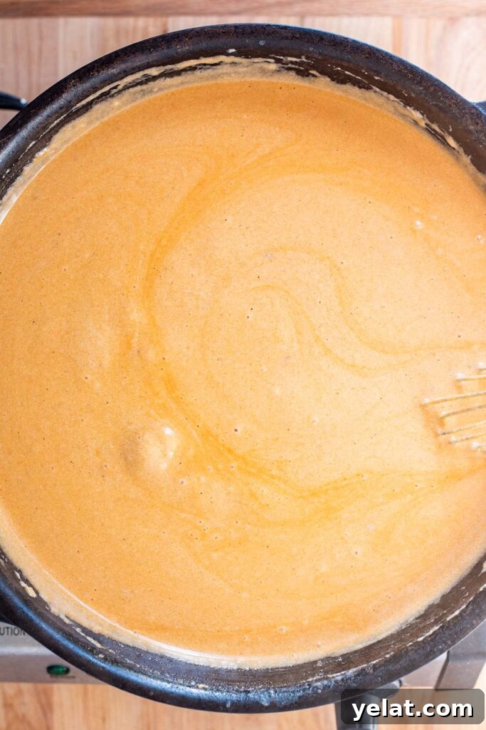 Skillet Buffalo Chicken Macaroni and Cheese Recipe 16 A creamy orange buffalo and cheese sauce cooking in a cast iron skillet.