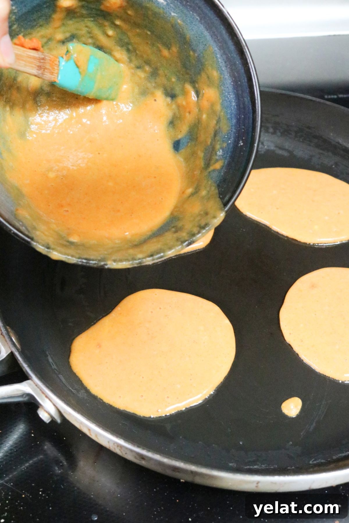 Raw pumpkin pancake batter being poured into a pan.