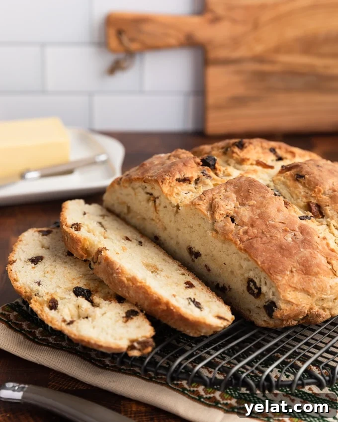 Classic Irish-American Soda Bread Recipe for Homemade Loaves 2 sliced loaf of American-style Irish Soda bread with raisins on a wire cooling rack, with a block of Irish butter in the background