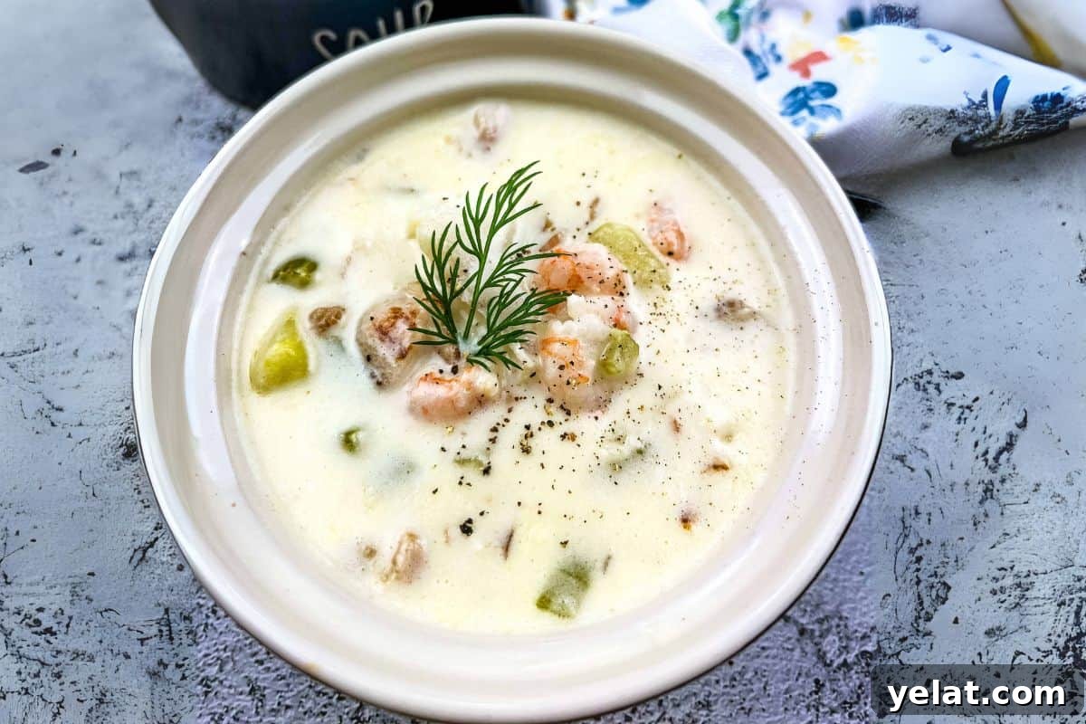 A bowl of fully loaded seafood chowder garnished with fresh dill and cracked pepper on top.