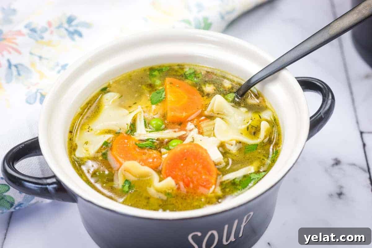 A bowl of Rotisserie Chicken Noodle Soup with a spoon resting inside.