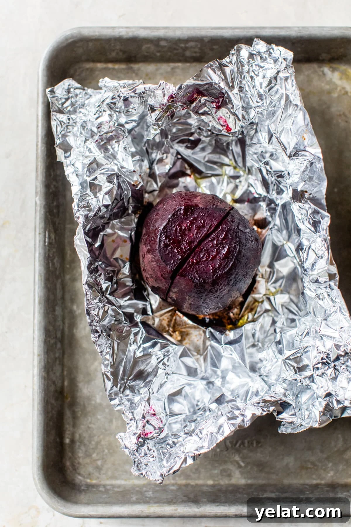 a roasted beet on aluminum foil on a baking sheet