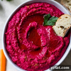 beet hummus in a bowl with a slice of bread on top and bread