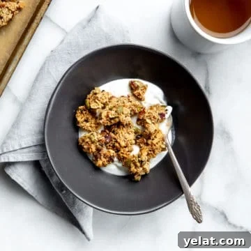 A bowl of granola clusters in a bowl over yogurt with a cup of tea alongside.