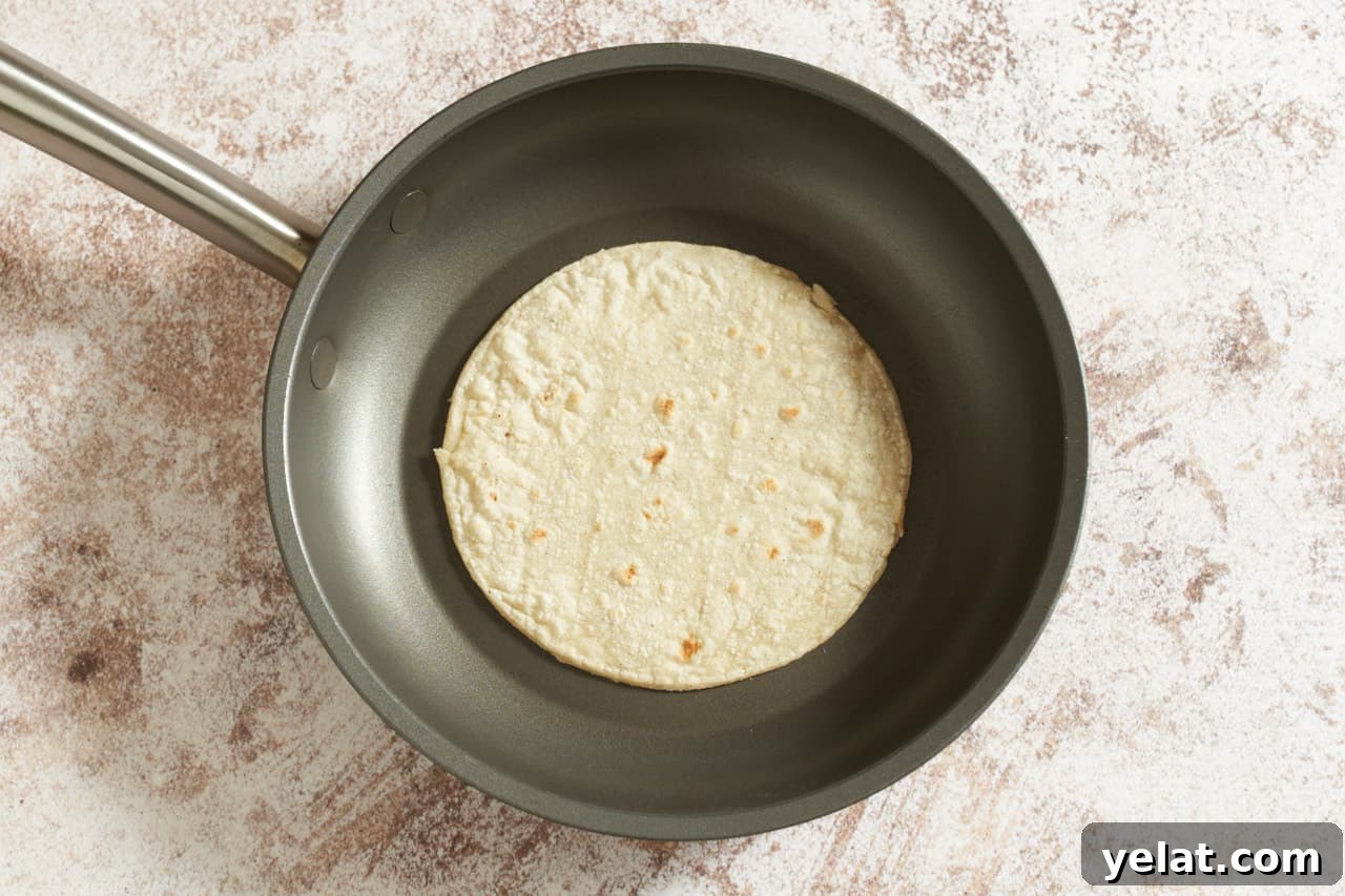 A corn tortilla in a non-stick skillet.