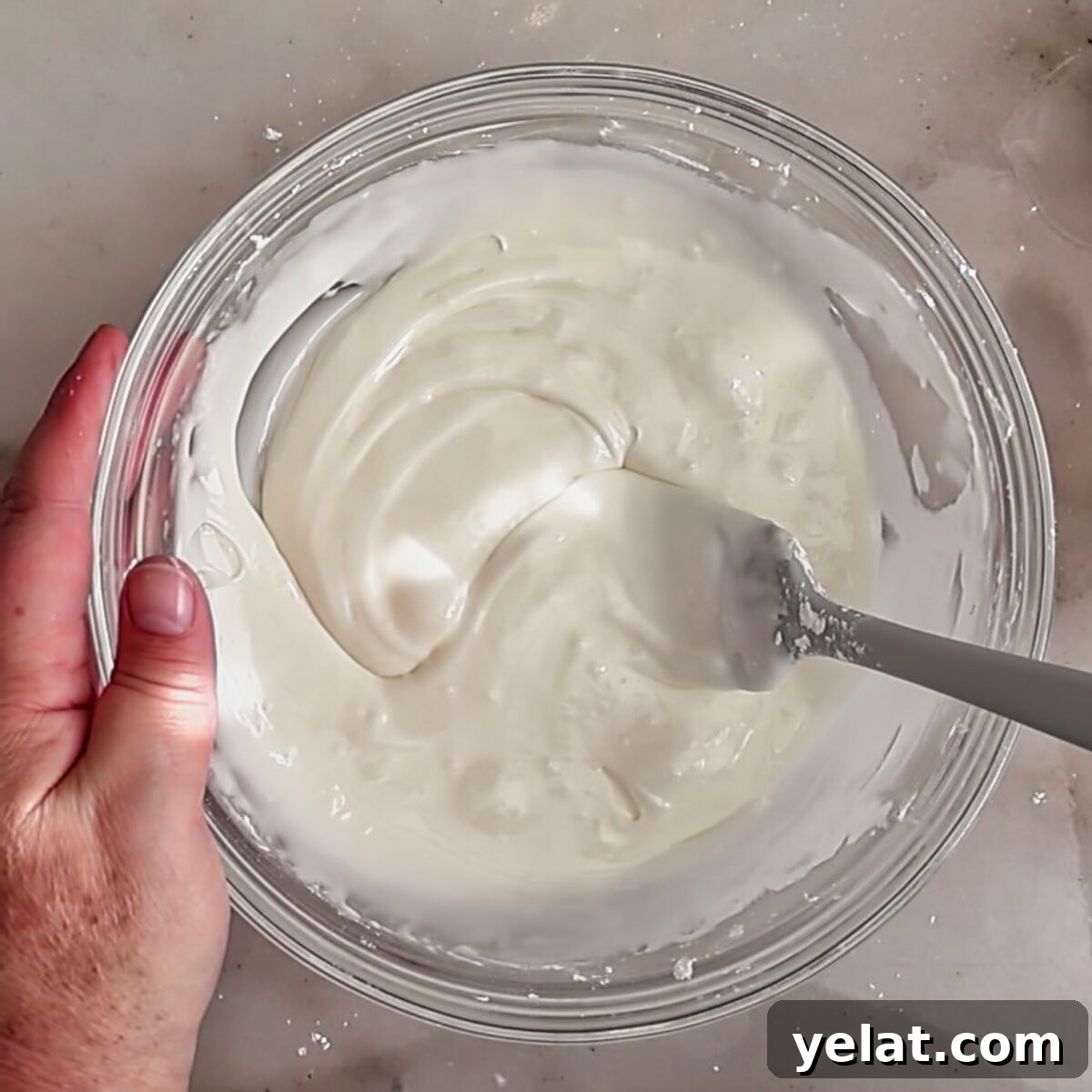 Irresistible Gluten-Free Ricotta Cookie Recipe 10 stirring white frosting in glass bowl.