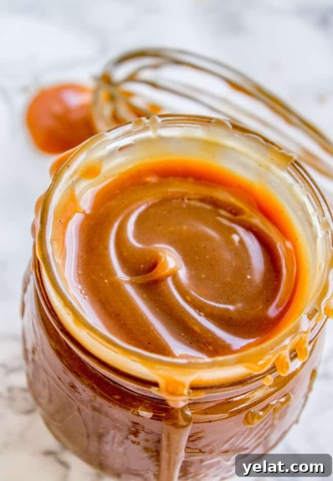 Homemade Caramel Sauce Recipe for Rich, Smooth Results 5 a mason jar of homemade caramel sauce with a whisk in the background.