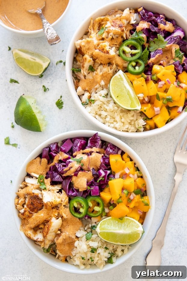 taco bowl overhead shot of two healthy fish taco bowls with baked white fish, mango salsa, slaw and cauliflower rice