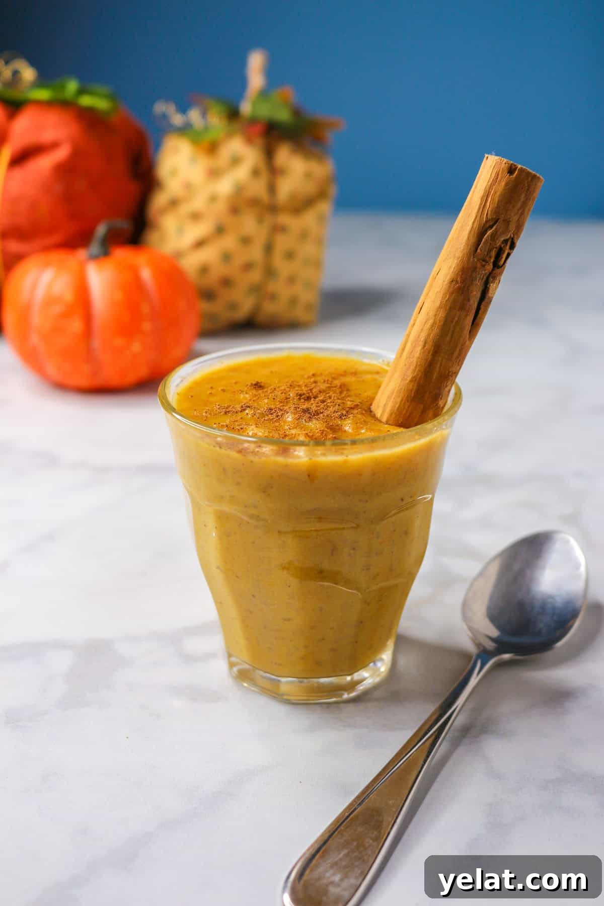 Pumpkin arroz con leche in a glass cup garnished with a cinnamon stick