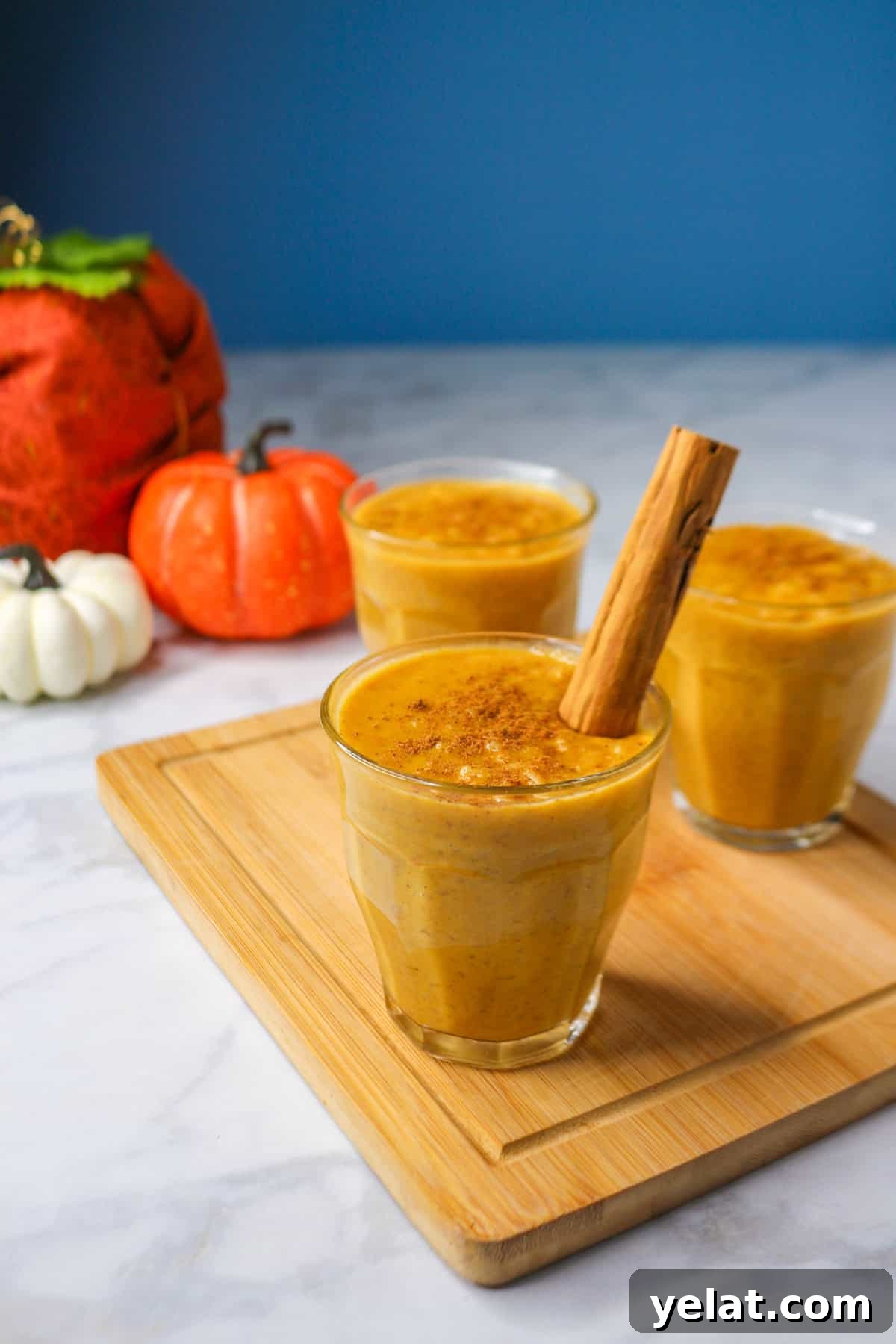 Pumpkin arroz con leche in a glass cup on a small wooden board garnished with a cinnamon stick