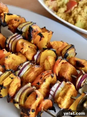Grilled Chicken Kabob Skewers on a plate with couscous in the background.
