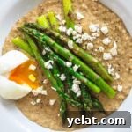 Soft-Boiled Egg and Asparagus Over Savory Oats 3 A top down view of a bowl of oatmeal with egg, asparagus and feta cheese.