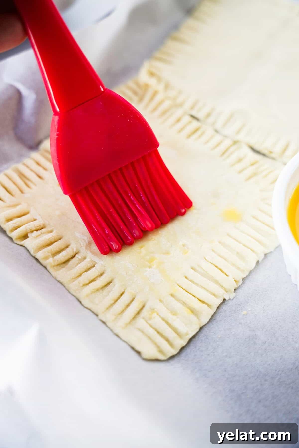 Spicy Pineapple Tart Recipe: Sweet and Tangy Baked Cookies 9 pastry brush brushing on melted butter to puff pastry