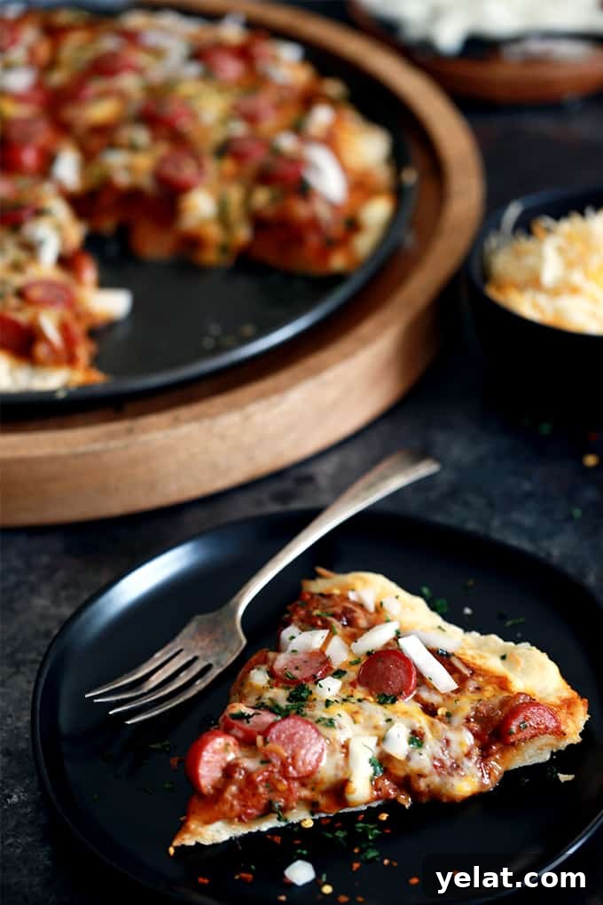 A slice of Chili Cheese Dog Pizza lifted to show gooey cheese. A slice of Chili Cheese Dog Pizza lifted to show gooey cheese.