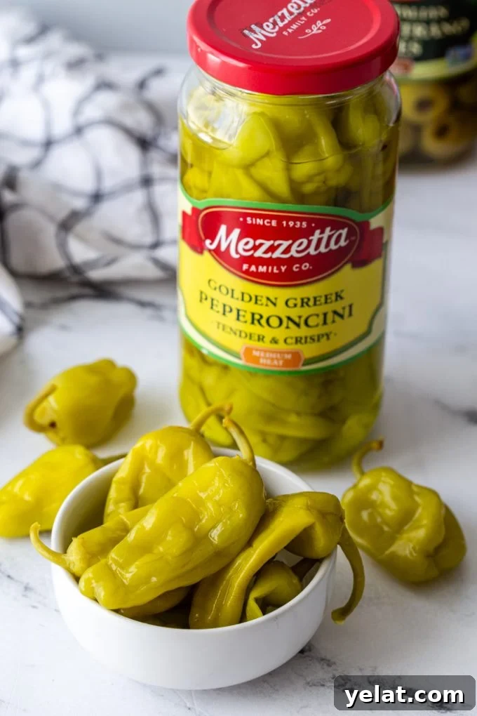 jar of mezzetta golden greek peperoncini peppers with a bowl of peppers in front of it