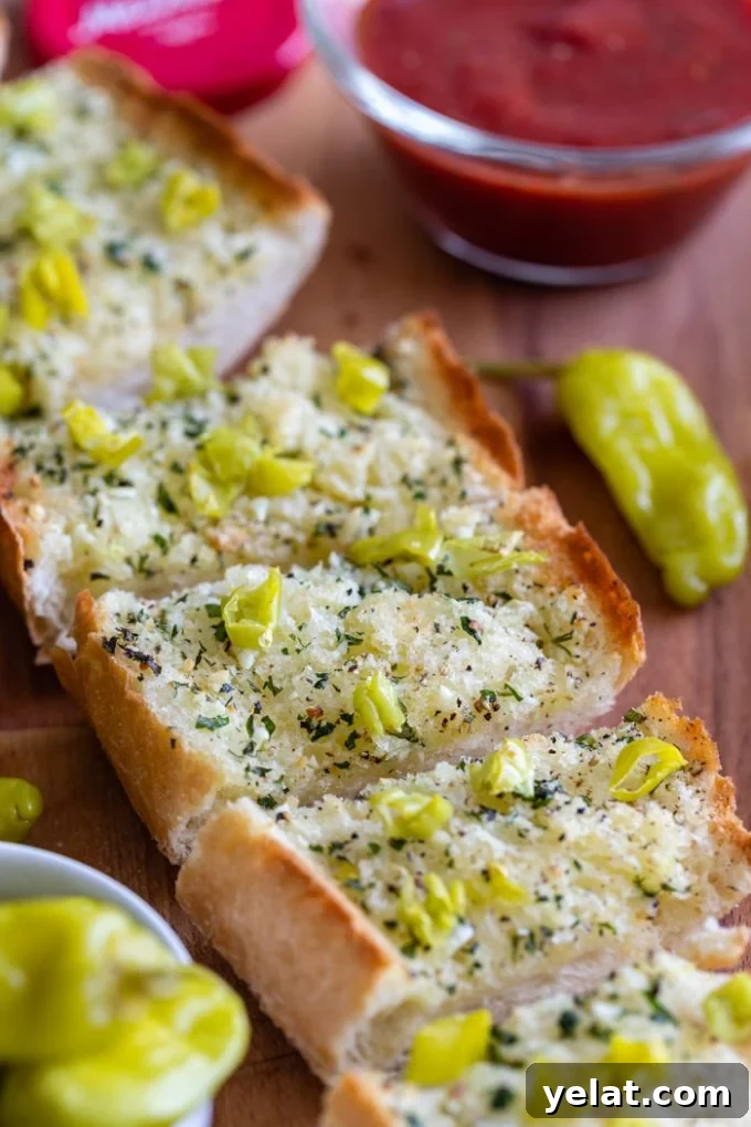 sliced garlic bread topped with chopped peperoncini peppers. marinara sauce in the corner