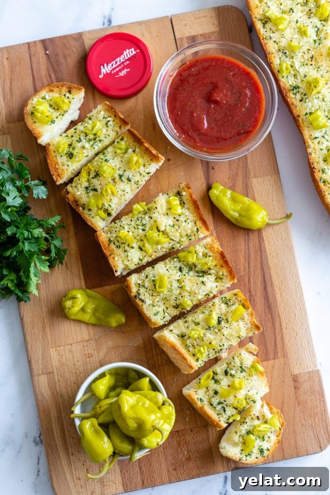 sliced garlic bread topped with chopped peperoncini peppers. marinara sauce in the corner