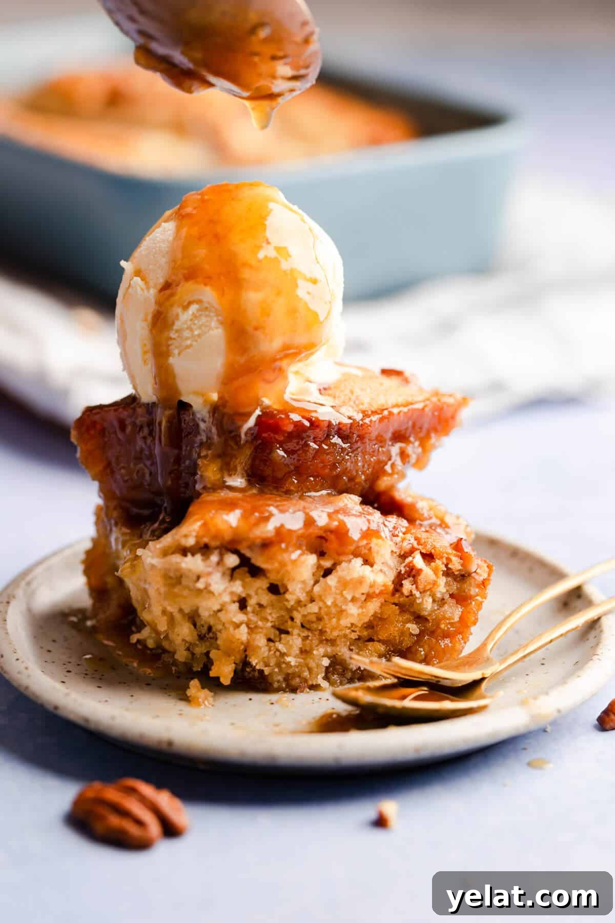 Self-Saucing Banana Pudding Recipe with Gooey Caramel Sauce 9 side angle photo of slice of banana pudding topped with ice cream and drizzled with sticky sauce