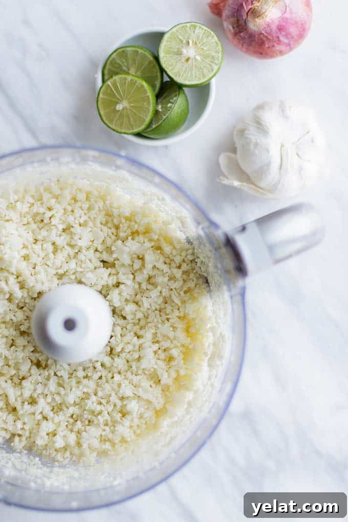 Authentic Mexican Cauliflower Rice Recipe for Flavorful Low-Carb Meals 4 A food processor bowl filled with cauliflower processed into rice.
