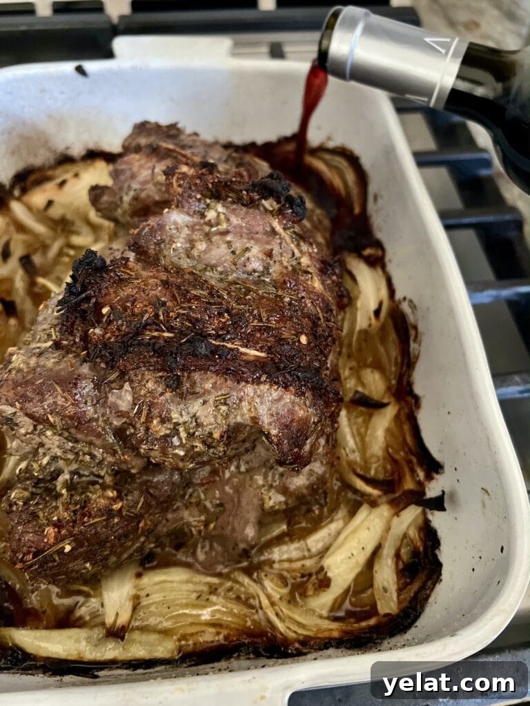 Slow-Roasted Mediterranean Lamb Shoulder Recipe 12 Pouring dry red wine into baking dish after the lamb has cooked for one hour uncovered at high heat.