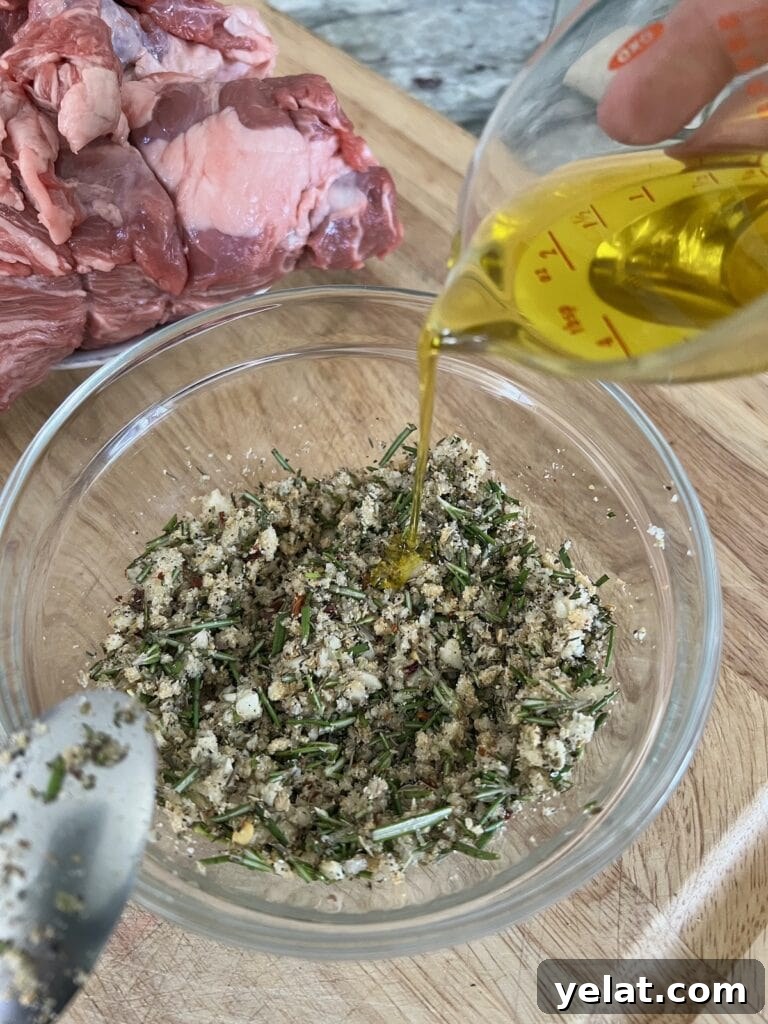 Slow-Roasted Mediterranean Lamb Shoulder Recipe 6 Making the marinade by pouring extra virgin olive oil into herb/garlic/spice mixture in white bowl.