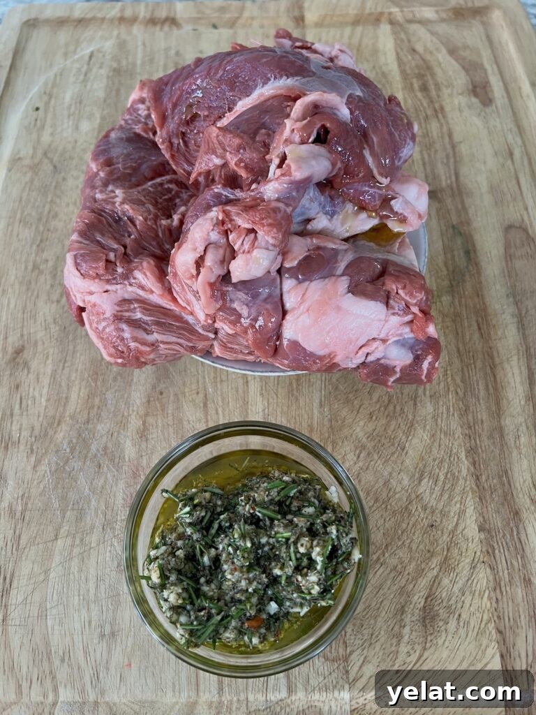 Slow-Roasted Mediterranean Lamb Shoulder Recipe 7 Lamb marinade in glass bowl next to boneless lamb shoulder.