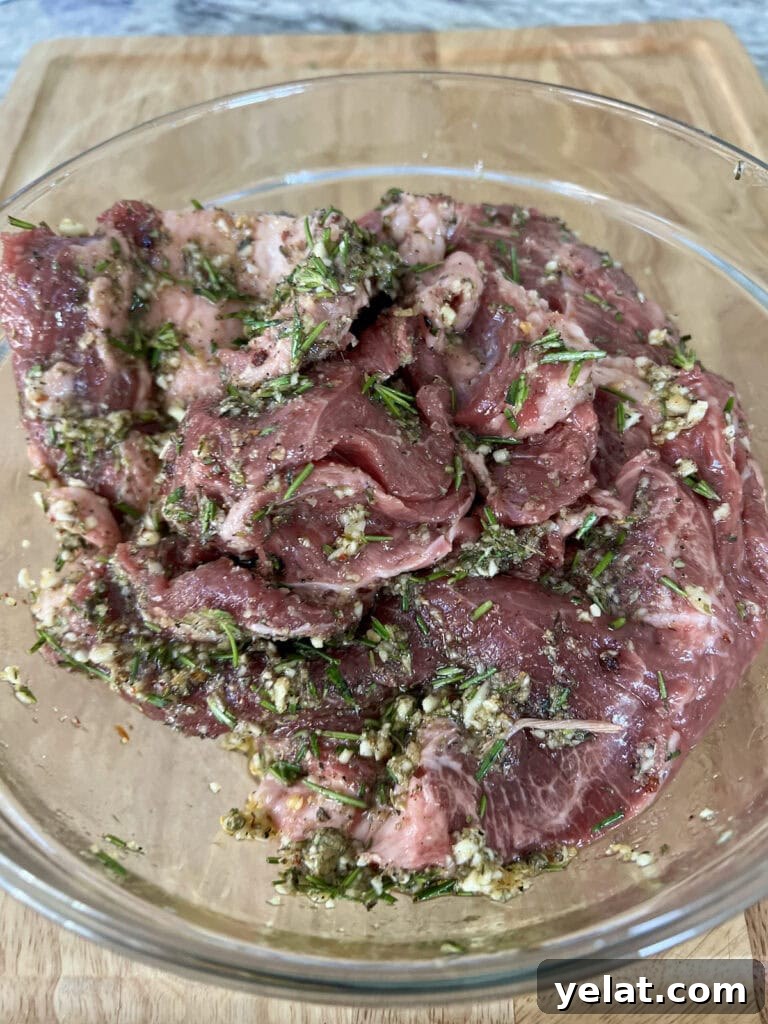 Slow-Roasted Mediterranean Lamb Shoulder Recipe 8 Lamb shoulder rubbed with marinade in glass bowl.