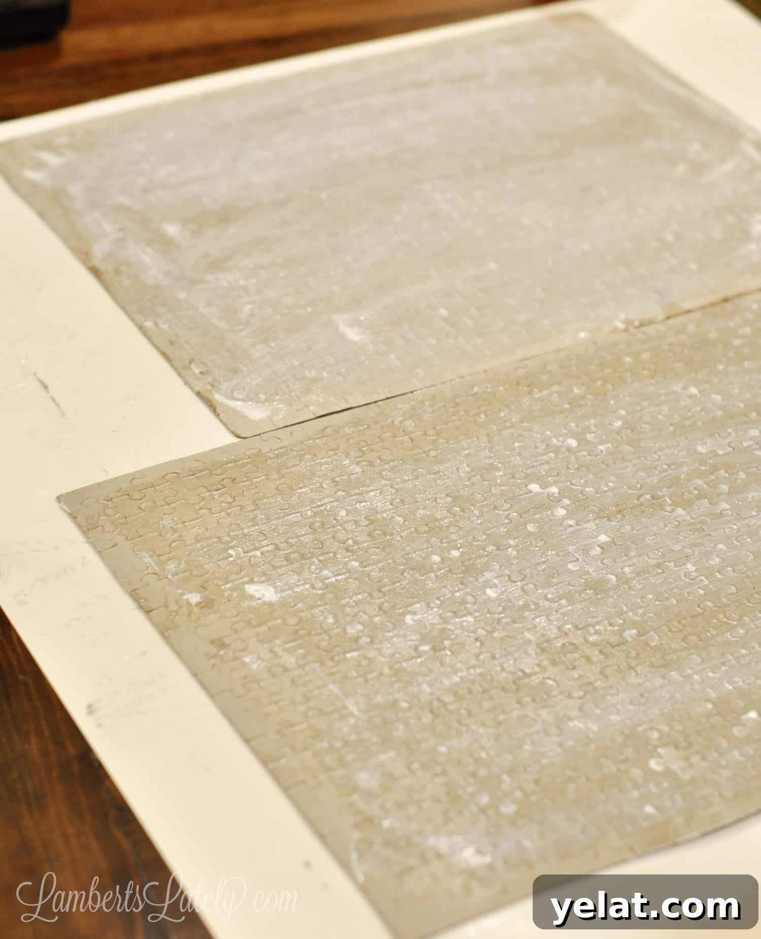 How to Glue and Hang a Puzzle Without a Frame 11 jigsaw puzzles turned over on a piece of poster board, covered in a thin layer of mod podge glue that isn't dried.