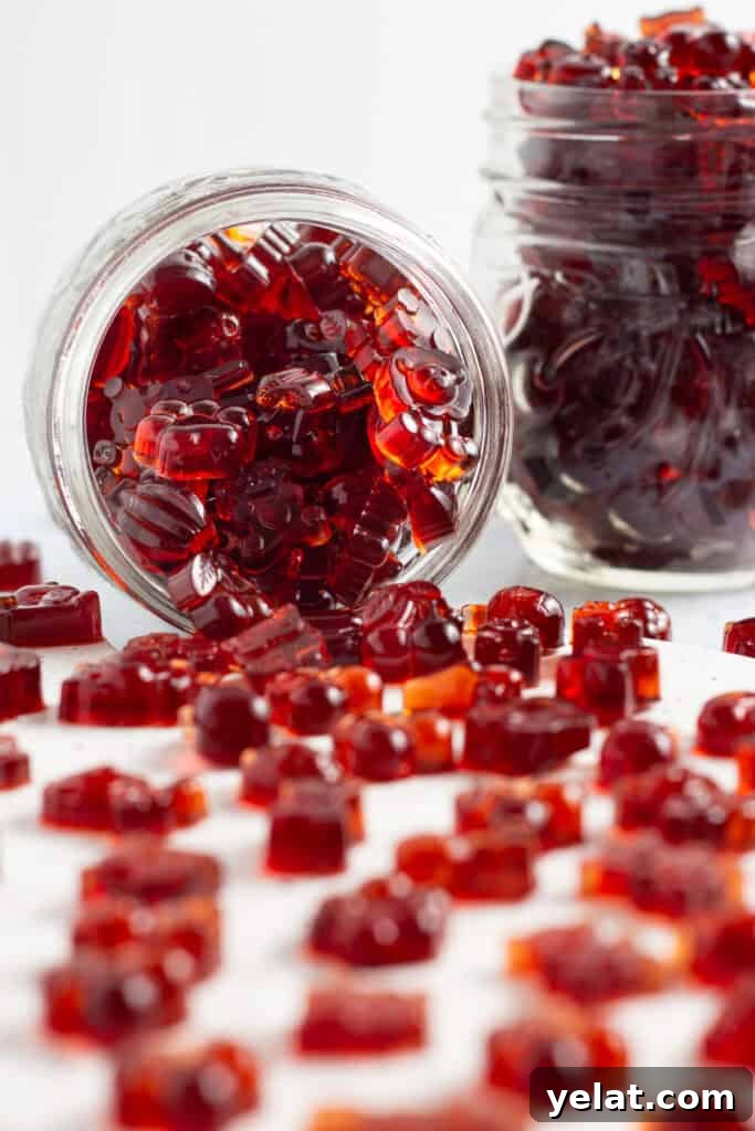 Tart Cherry Gummies for Sleep, Recovery & Joint Support 2 Side view of a jar of tart cherry gummies, with cherry gummies spilling out onto a white countertop.