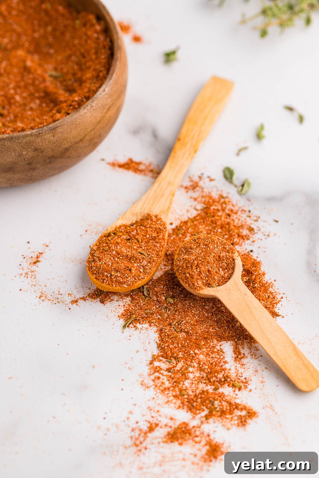 15 Homemade Seasoning Recipes to Transform Your Cooking 2 Small wooden measuring spoon and larger wooden spoon containing seasoning mixture with seasoning on surface and wooden bowl with seasoning in background
