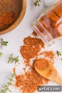 15 Homemade Seasoning Recipes to Transform Your Cooking 19 wooden bowl with small amount of seasonings, white glass container tipped over with seasonings on surface and wooden spoon