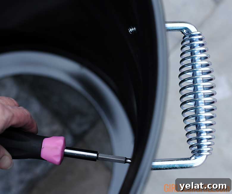 Barrel House Cooker 18C Review: Features, Performance & Verdict 6 using a pink screwdriver to tighten a handle to a grill