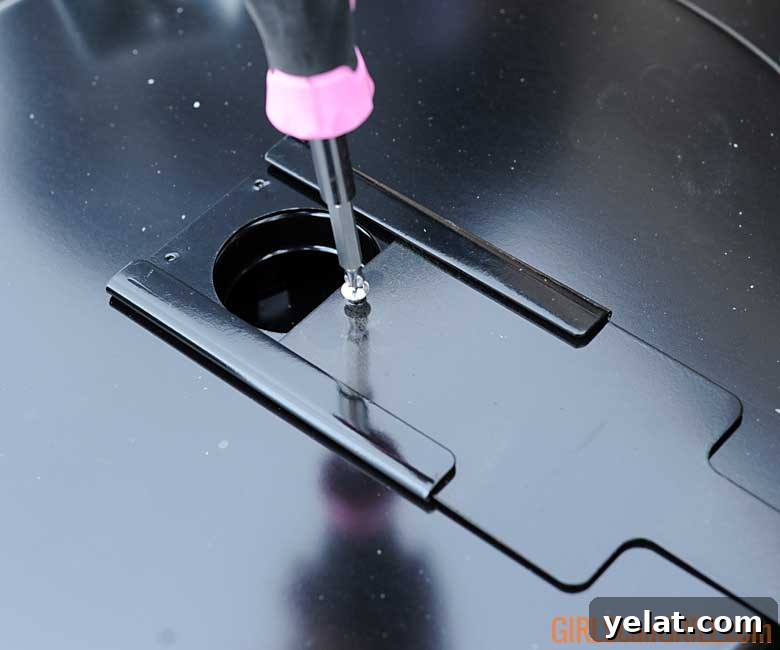 Barrel House Cooker 18C Review: Features, Performance & Verdict 8 using a pink screwdriver to tighten a damper to a grill