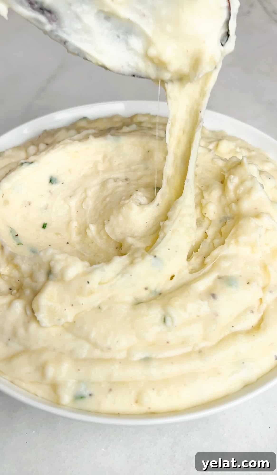 Cheesy Boursin mashed potatoes hanging off a spoon over a bowl