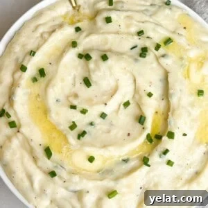 A bowl of whipped Boursin mashed potatoes with pats of butter